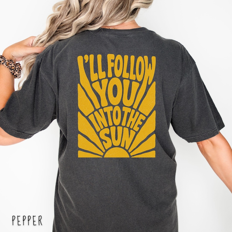 Może przedstawiać: Ciemnoszara koszulka z ż&oacute;łtą grafiką na plecach z napisem "I'll Follow You Into The Sun". Grafika jest w stylu retro i przedstawia słońce. Słowo "Pepper" jest wydrukowane na dole.