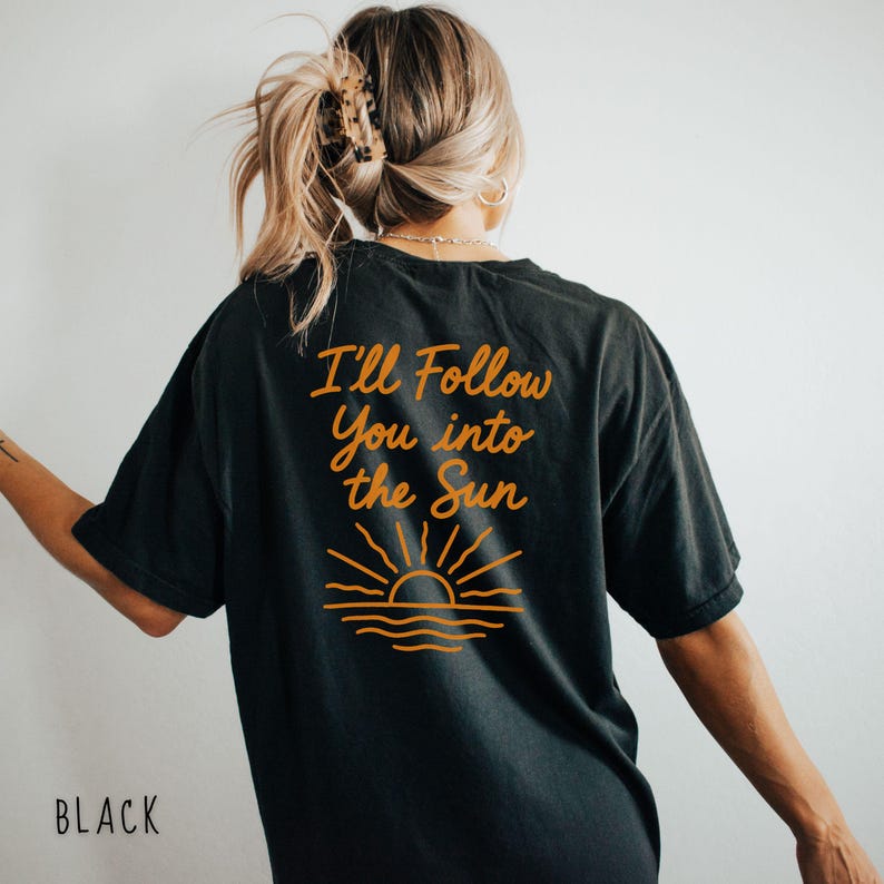 May include: Black t-shirt with the text "I'll Follow You into the Sun" in orange script. Below the text is an orange graphic of a sun setting over the ocean. The word "BLACK" is printed at the bottom.