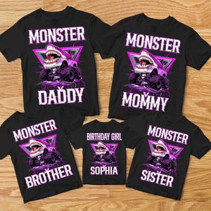 May include: Black t-shirts with a monster truck design featuring a shark head. The shirts have the words "MONSTER" and "DADDY", "MOMMY", "BROTHER", "SISTER", and "BIRTHDAY GIRL SOPHIA" in white.