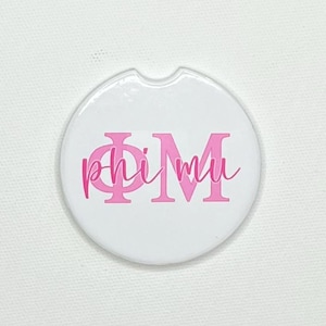 Puede incluir: Posavasos blanco para coche con diseño rosa "Phi Mu". El posavasos redondo tiene una pequeña muesca para facilitar la extracción del portavasos del coche. Las letras son en negrita, en bloque, con una superposición de "mu" en cursiva.