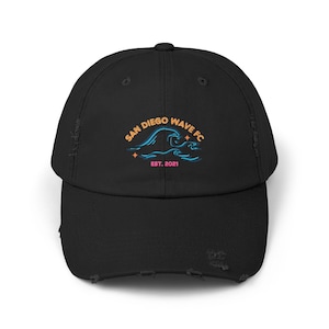 May include: Black distressed baseball cap with a white and blue wave graphic and the text "San Diego Wave FC Est. 2021" in orange.