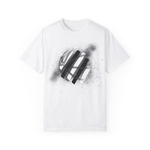 May include: White t-shirt with a black and white graphic of a basketball with a spray paint effect.