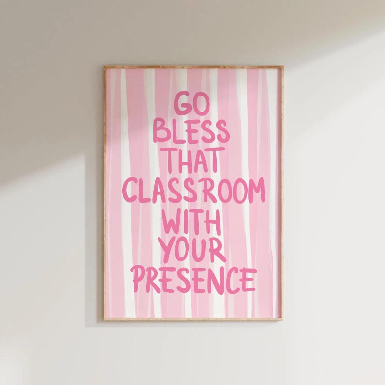May include: A framed print with a pink and white striped background. The text "GO BLESS THAT CLASSROOM WITH YOUR PRESENCE" is written in pink, bold letters. The artwork is in a wooden frame.