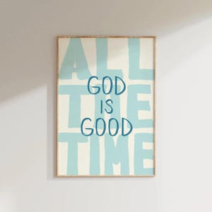 May include: A framed art print with the words "ALL THE TIME GOD IS GOOD" in blue lettering on a cream background. The words are arranged in a block letter style with a light blue background.