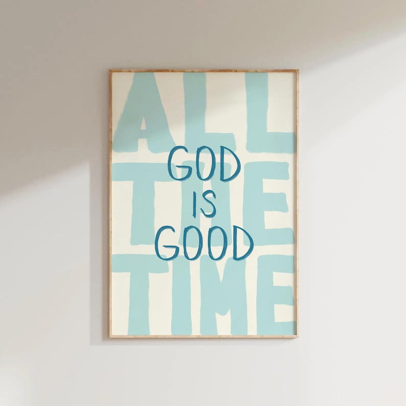 May include: A framed art print with the words "ALL THE TIME GOD IS GOOD" in blue lettering on a cream background. The words are arranged in a block letter style with a light blue background.