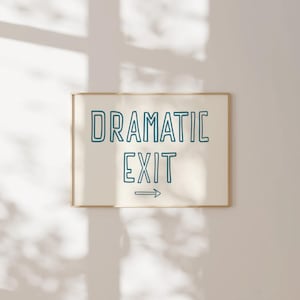 May include: A white framed print with the text "DRAMATIC EXIT" in blue outlined lettering with an arrow pointing to the right.