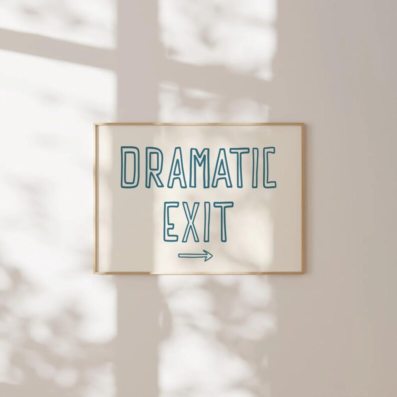 May include: A white framed print with the text "DRAMATIC EXIT" in blue outlined lettering with an arrow pointing to the right.