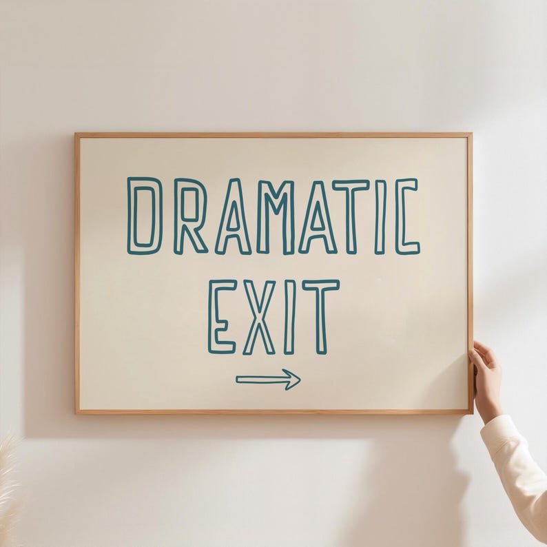 May include: A framed sign with a white background and a teal blue outline. The sign reads "Dramatic Exit" with an arrow pointing to the right.