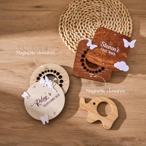 May include: Wooden tooth fairy boxes and a wooden elephant-shaped teether are displayed on a wooden surface. One box is round and another is square, both with magnetic closures. The round box is labelled "Riley's Tooth Fairy Box". The square box is labelled "Steven's First Teeth".