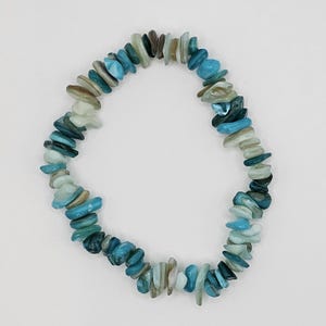 May include: A blue and white shell bracelet with a stretchy elastic band.