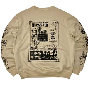 Puede incluir: Sudadera beige de cuello redondo con un gráfico negro del juego "Heroes III of Might and Magic". El gráfico incluye el título del juego, una ilustración de castillo e iconos del juego. Las mangas tienen ilustraciones negras de criaturas fantásticas.