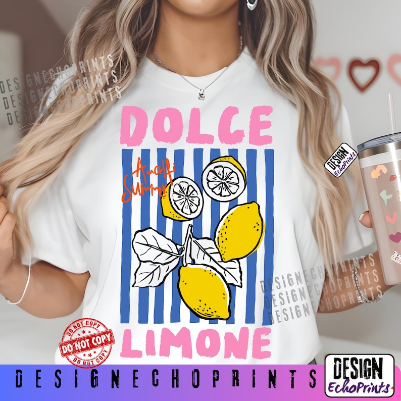 Puede incluir: Camiseta blanca con un dise&ntilde;o gr&aacute;fico que presenta la palabra "DOLCE" en rosa, "Amalfi Summer" en naranja y "LIMONE" en azul. El dise&ntilde;o incluye ilustraciones de limones y rayas verticales azules.