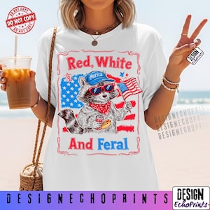 Puede incluir: Camiseta blanca con un dise&ntilde;o de mapache con gafas de sol, pa&ntilde;uelo y gorra de b&eacute;isbol, sosteniendo un perrito caliente y una bandera americana. La camiseta tiene el texto "Red, White, And Feral" con un tema patri&oacute;tico.