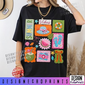 May include: Black t-shirt featuring a colorful summer-themed graphic. The design includes images of a hat, watermelon, flip-flops, a camera, and a bow, with the word "Summer" and "Vibes". The shirt has a relaxed fit.