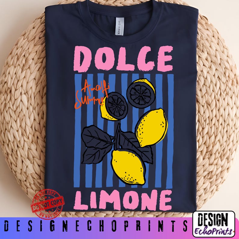 Puede incluir: Camiseta azul marino con un dise&ntilde;o gr&aacute;fico. El dise&ntilde;o presenta las palabras "DOLCE LIMONE" en rosa y "Amalfi Summer" en naranja. El dise&ntilde;o incluye limones amarillos y rayas verticales azules. La camiseta se muestra sobre una superficie tejida.