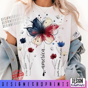 K&ouml;nnte beinhalten: Wei&szlig;es T-Shirt mit einem floralen Design in den Farben Rot, Wei&szlig; und Blau. Das Wort "america" ist in Schreibschrift geschrieben. Das Design enth&auml;lt auch den Text "faith freedom & pride" und "1776-2026" sowie Schmetterlinge und Sterne.