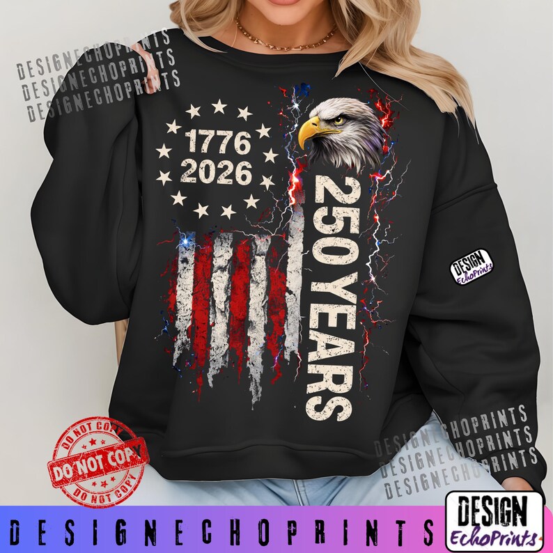 Puede incluir: Sudadera negra con un dise&ntilde;o de bandera estadounidense desgastada, el texto "1776 2026" y "250 YEARS". El dise&ntilde;o incluye una cabeza de &aacute;guila y rayos. La sudadera tiene mangas largas.