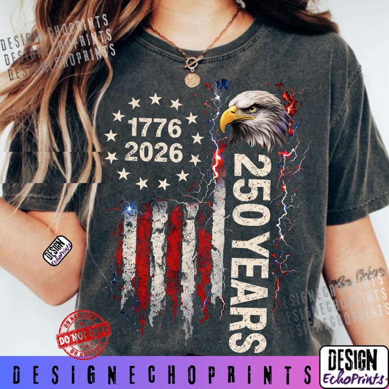 Puede incluir: Camiseta gris oscuro con un dise&ntilde;o de la bandera estadounidense, el texto "1776 2026" y "250 YEARS". El dise&ntilde;o incluye una cabeza de &aacute;guila y rayos. La camiseta tiene un aspecto desgastado.
