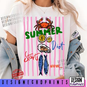 Puede incluir: Camiseta blanca con un dise&ntilde;o gr&aacute;fico que presenta un cangrejo, rodajas de lim&oacute;n, una ostra y dos peces. El texto "SUMMER Diet Starts NOW" se muestra en varios colores sobre un fondo de rayas rosas. La camiseta tiene cuello redondo.