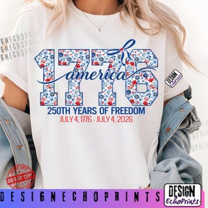 Puede incluir: Camiseta blanca con el texto "1776 america" en un dise&ntilde;o floral con flores rojas, blancas y azules. La camiseta tambi&eacute;n incluye el texto "250TH YEARS OF FREEDOM JULY 4, 1776 - JULY 4, 2026".