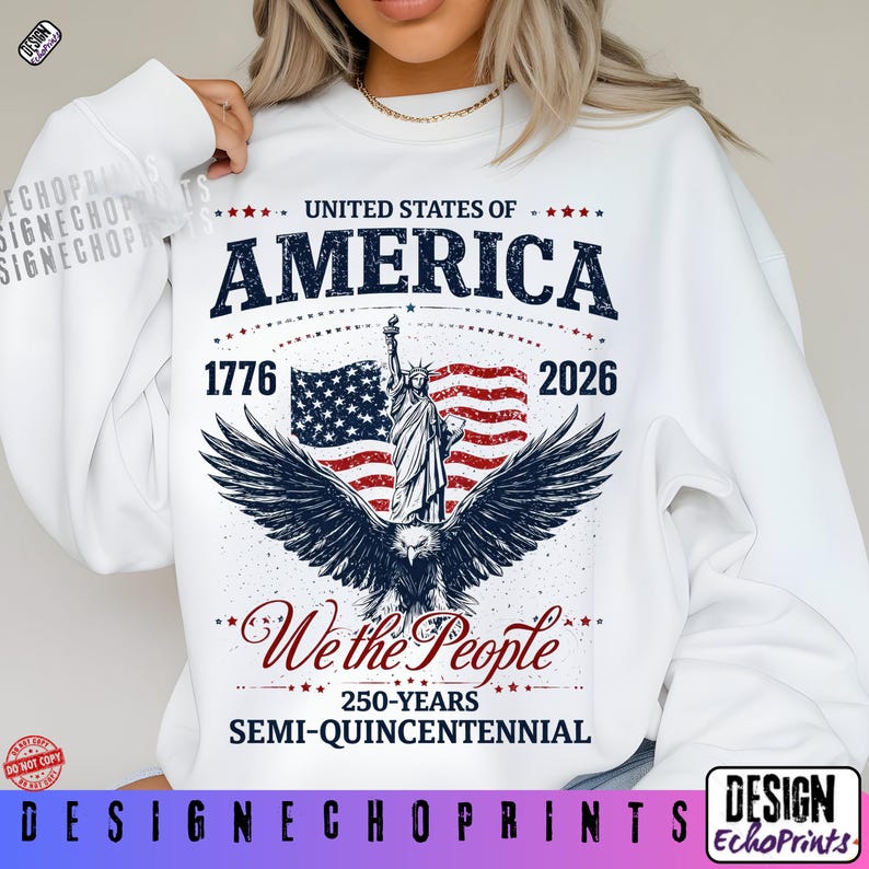 Puede incluir: Sudadera blanca con un dise&ntilde;o patri&oacute;tico. El gr&aacute;fico incluye el texto "United States of America 1776-2026", una bandera, la Estatua de la Libertad y un &aacute;guila. Tambi&eacute;n aparece la frase "We the People".