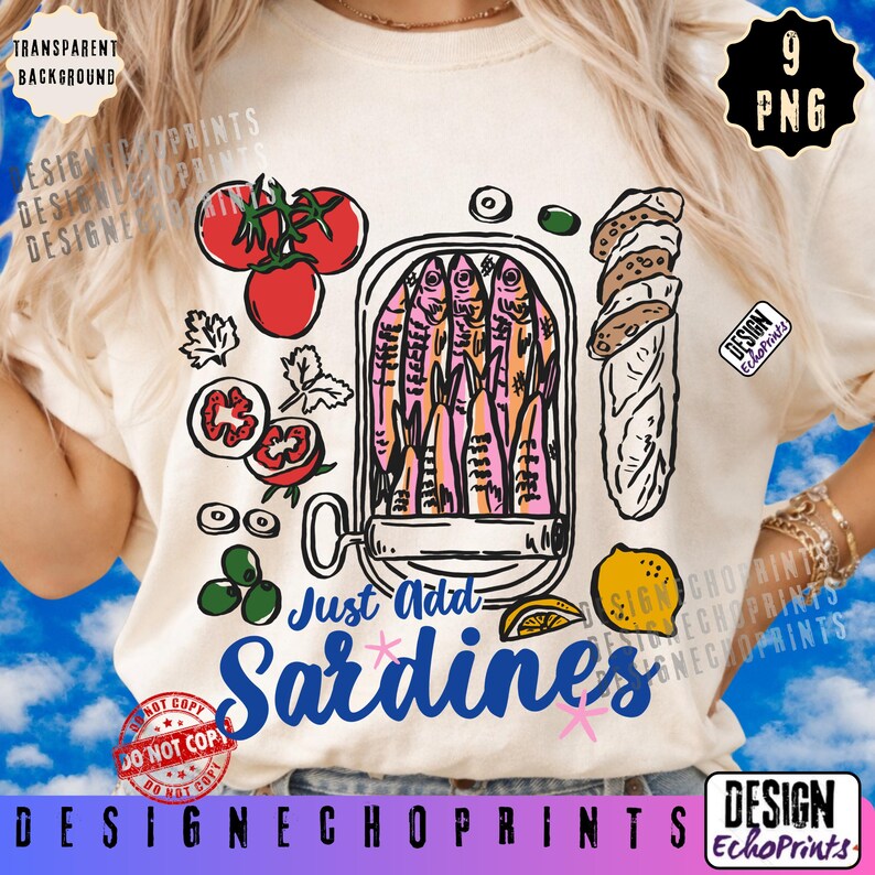 Puede incluir: Camiseta color crema con un dise&ntilde;o de sardinas colorido. El gr&aacute;fico incluye una lata de sardinas, tomates, aceitunas, pan y el texto "Just Add Sardines". Tambi&eacute;n se ve una rodaja de lim&oacute;n y las palabras "Design EchoPrints".