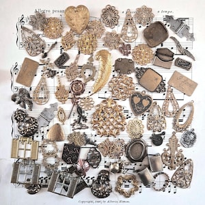 May include: A collection of assorted metal charms, filigree components, and decorative findings in various gold, silver, and bronze tones. The items include heart shapes, a feather, rectangular plates with the text I Love You, and window frames.