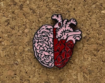 Könnte beinhalten: Eine rosa und rote Emaille-Anstecknadel, die ein Gehirn und ein Herz zeigt, die miteinander verschmolzen sind. Das Gehirn befindet sich auf der linken Seite und das Herz auf der rechten Seite.