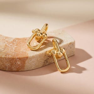 Könnte beinhalten: Eine weiße Keramik-Tasse mit schwarzem Henkel und dem Text "But First, Coffee" in handschriftlichem Stil. Die Tasse steht auf einer weißen Oberfläche. Die Tasse ist etwa 10 cm hoch.