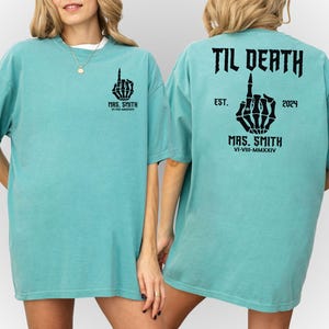 Może przedstawiać: Turkusowy t-shirt z szkieletową ręką pokazującą środkowy palec i tekstem "Til Death"  "MRS. SMITH" "EST. 2024" "MRS. SMITH" "VI-VIII-MMXXIV"