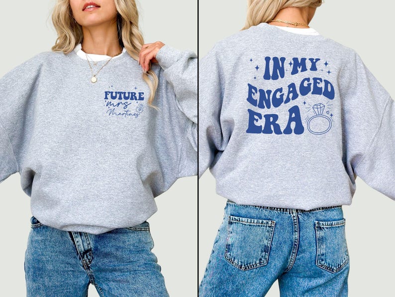 May include: Grey sweatshirt with the text "Future Mrs. Martinez" on the front and "In My Engaged Era" on the back. The sweatshirt has a ring and diamond graphic on the back.