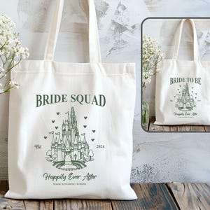 May include: Two white canvas tote bags with a green outline of Cinderella's castle and text. The bag on the left says "Bride Squad" and the bag on the right says "Bride to Be". Both bags have the text "Happily Ever After" and the location "Magic Kingdom, Florida".