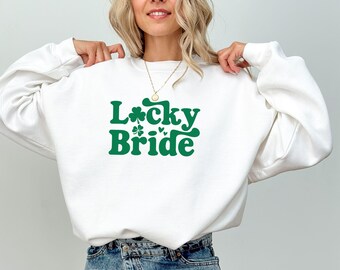 May include: White sweatshirt with a green shamrock and the text "Lucky Bride" in a retro font.
