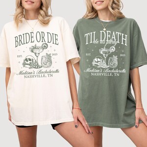 Peut inclure: Deux t-shirts blancs avec un motif vert et blanc. Le texte sur les t-shirts est "Bride or Die" et "Til Death do us party". Les deux t-shirts ont un motif de cr&acirc;ne et d'os crois&eacute;s avec un verre &agrave; cocktail. Le texte comprend &eacute;galement "Madison's Bachelorette, Nashville, TN" et l'ann&eacute;e "2025".