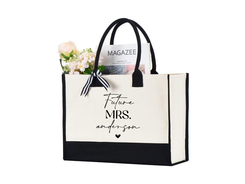Op de afbeelding: Een witte canvas tote bag met zwarte bies en handvatten. De tas heeft de tekst "Future Mrs. Anderson" in het zwart op de voorkant gedrukt.