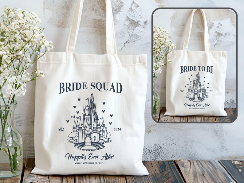 May include: Two white canvas tote bags with black text and a black outline of Cinderella's castle. The bag on the left says "Bride Squad" and the bag on the right says "Bride to Be". Both bags have the text "Happily Ever After" and "Magic Kingdom Florida" printed on them.