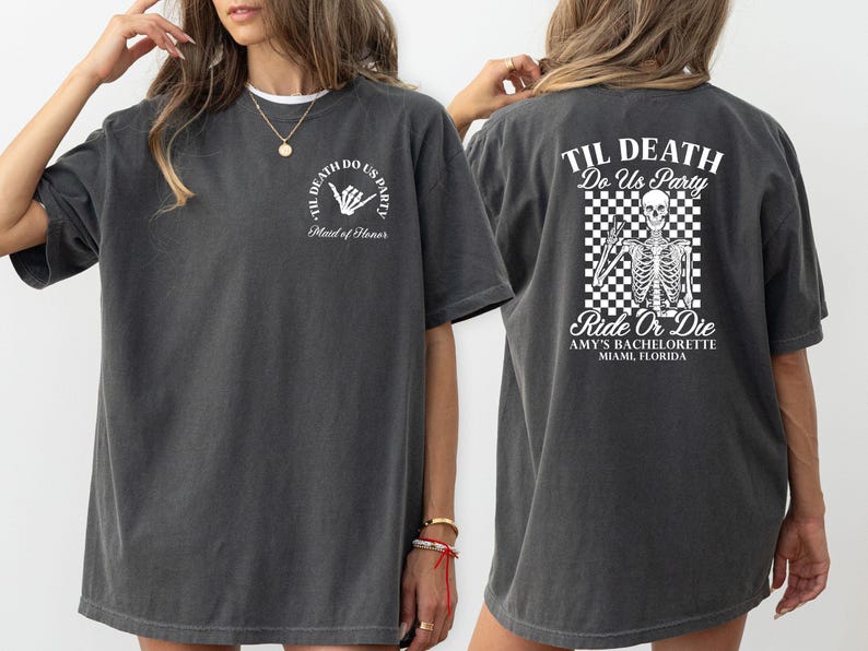 Może przedstawiać: Ciemnoszara koszulka z białym tekstem i grafiką. Prz&oacute;d koszulki m&oacute;wi "Til Death Do Us Party" z gestem dłoni i "Maid of Honor". Tył ma grafikę szkieletu oraz tekst "Ride or Die" i "Amy's Bachelorette Miami, Florida".