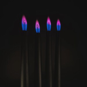 Close-up of romantic pink flame candles producing vivid pink flames, handmade for science fans, witches, and love manifestation.