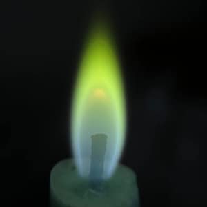 May include: A green candle with a yellow and blue flame burning.