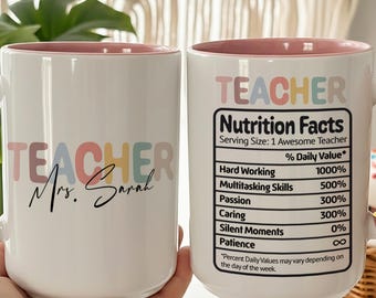 Könnte beinhalten: Weißer Keramikbecher mit rosa Henkel und Innenraum. Der Becher zeigt das Wort "TEACHER" in Pastellfarben und "Mrs. Sarah" in Schreibschrift. Die andere Seite zeigt ein "Nutrition Facts"-Etikett für Lehrer.