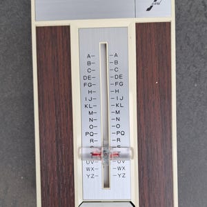 May include: Vintage address book with a cream, brown, and silver design. The address book has a sliding selector with letters A-Z. The brand name "carl" is printed on the top right corner.