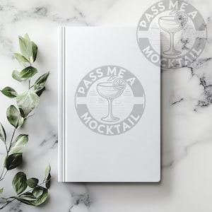 May include: White notebook with a gray graphic of a cocktail glass with a lime wedge and the text "Pass Me A Mocktail".