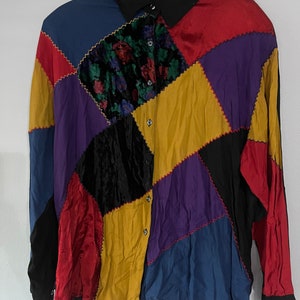 May include: A long-sleeved button-up shirt with a patchwork design. The shirt is made of different fabrics in various colors, including red, blue, yellow, purple, and black.