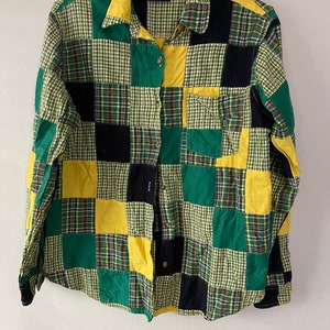 Puede incluir: Una camisa de manga larga con botones y diseño de patchwork. La camisa está hecha de diferentes telas a cuadros en verde, amarillo y negro.