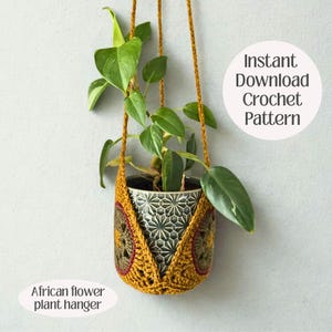 May include: A crocheted plant hanger in mustard yellow, holding a potted plant with green leaves. The hanger features an African flower design and the text "Instant Download Crochet Pattern" and "African flower plant hanger".