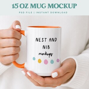 Puede incluir: Taza blanca de 443 ml con interior y asa naranja. La taza presenta el texto negro "NEST AND NIB mockups", con lunares de colores debajo. La parte superior de la imagen dice "15 OZ MUG MOCKUP".