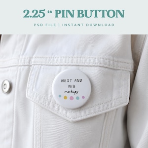 Könnte beinhalten: Ein weißer Ansteckbutton mit einem Durchmesser von ca. 5,7 cm mit dem Text "NEST AND NIB mockups" und Pastellpunkten, befestigt an einer weißen Jeansjacke. Der Text "2.25" PIN BUTTON" steht oben.