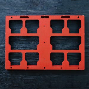 May include: A rectangular orange organiser tray featuring a symmetrical grid of eight cutouts, with four larger openings on the top and bottom rows and two elongated horizontal openings in the centre, including several small circular mounting holes.