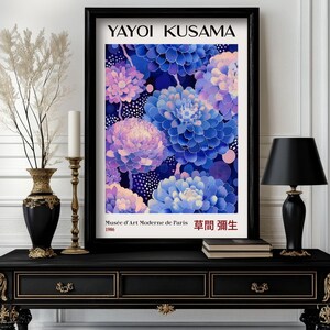May include: A black framed poster with a colourful floral design. The poster features the text "Yayoi Kusama" and "Musee d'Art Moderne de Paris 1986" in white text. The poster also features the text "草間彌生" in red text.