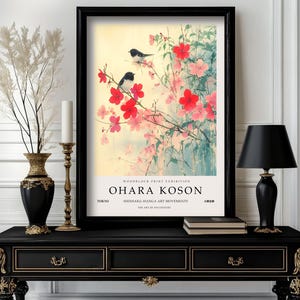 May include: A black framed print of a Japanese woodblock print featuring two black and white birds perched on a branch of pink and red blossoms. The print is titled "Ohara Koson" and includes the text "Woodblock Print Exhibition, Tokyo, Shinsaku-Hanga Art Movements, The Art of 20th Century".